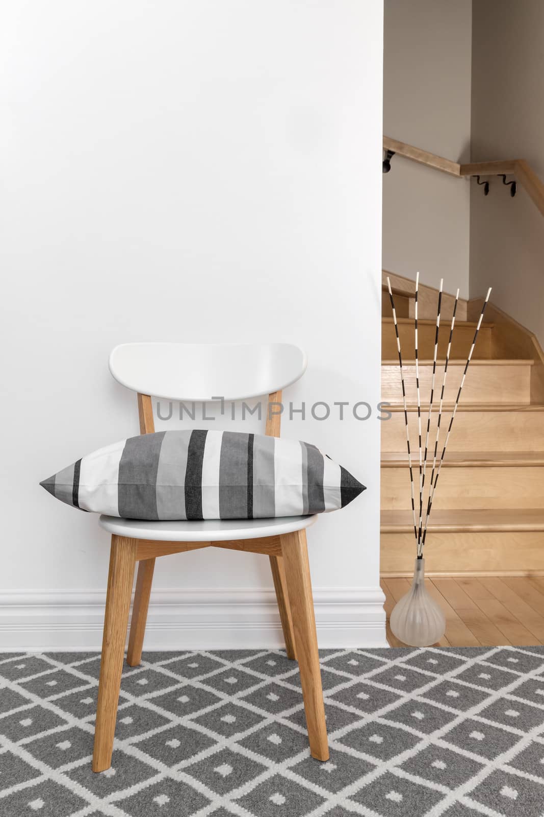Chair decorated with gray striped cushion in a room with staircase.