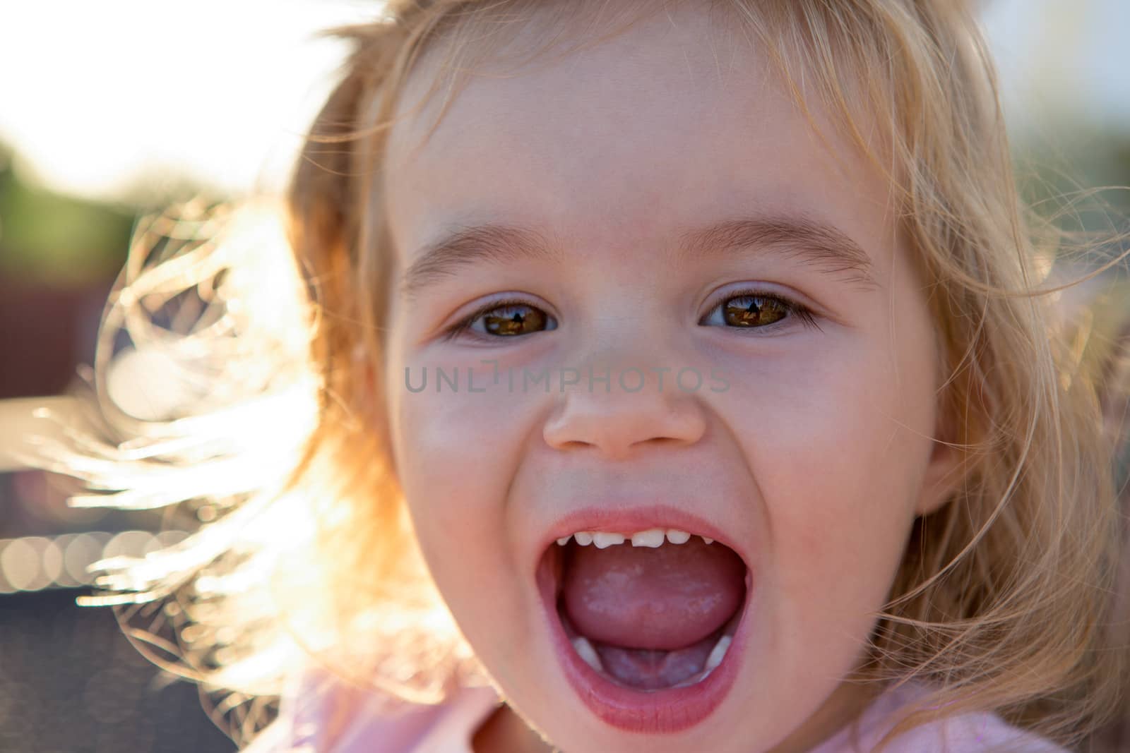 Little toddler girl laughing spontaneously while looking at you with showing her teeth