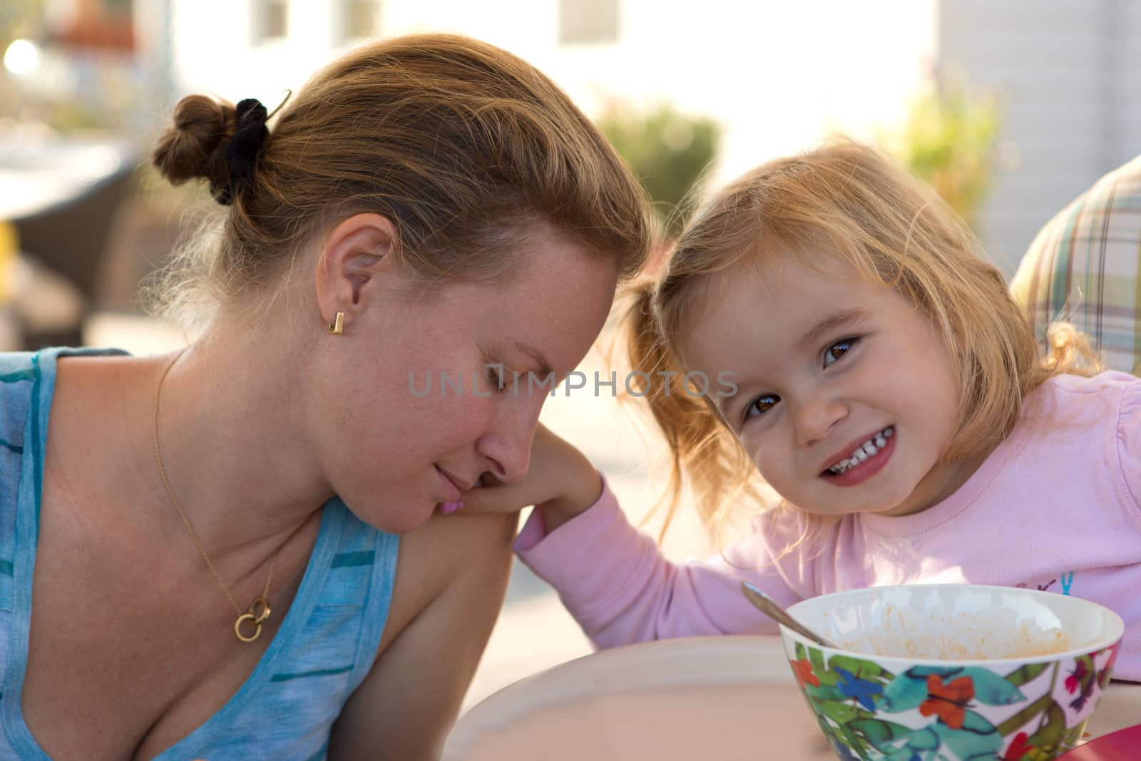 Little girl toddler touching her mothers shoulder softly while mother feels the love coming from her daughter