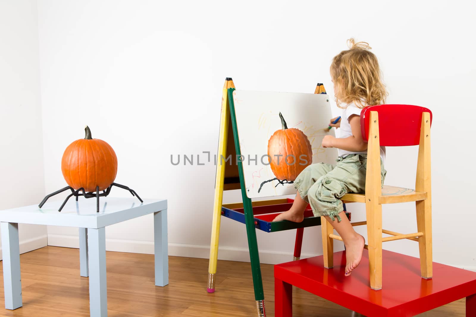 Little toddler girl painting pumpking on a whiteboard with a impressionist style