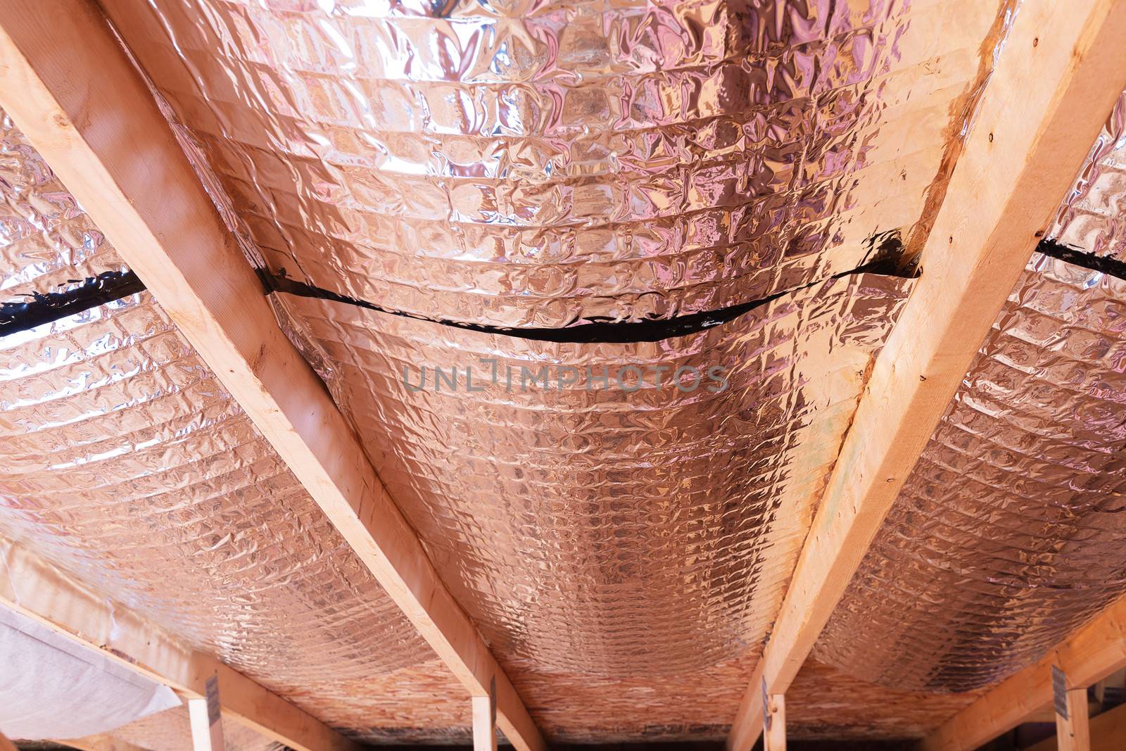 Insulating of attic with fiberglass cold barrier and reflective heat barrier used as baffle between the attic joists to increase the ventilation to reduce humidification