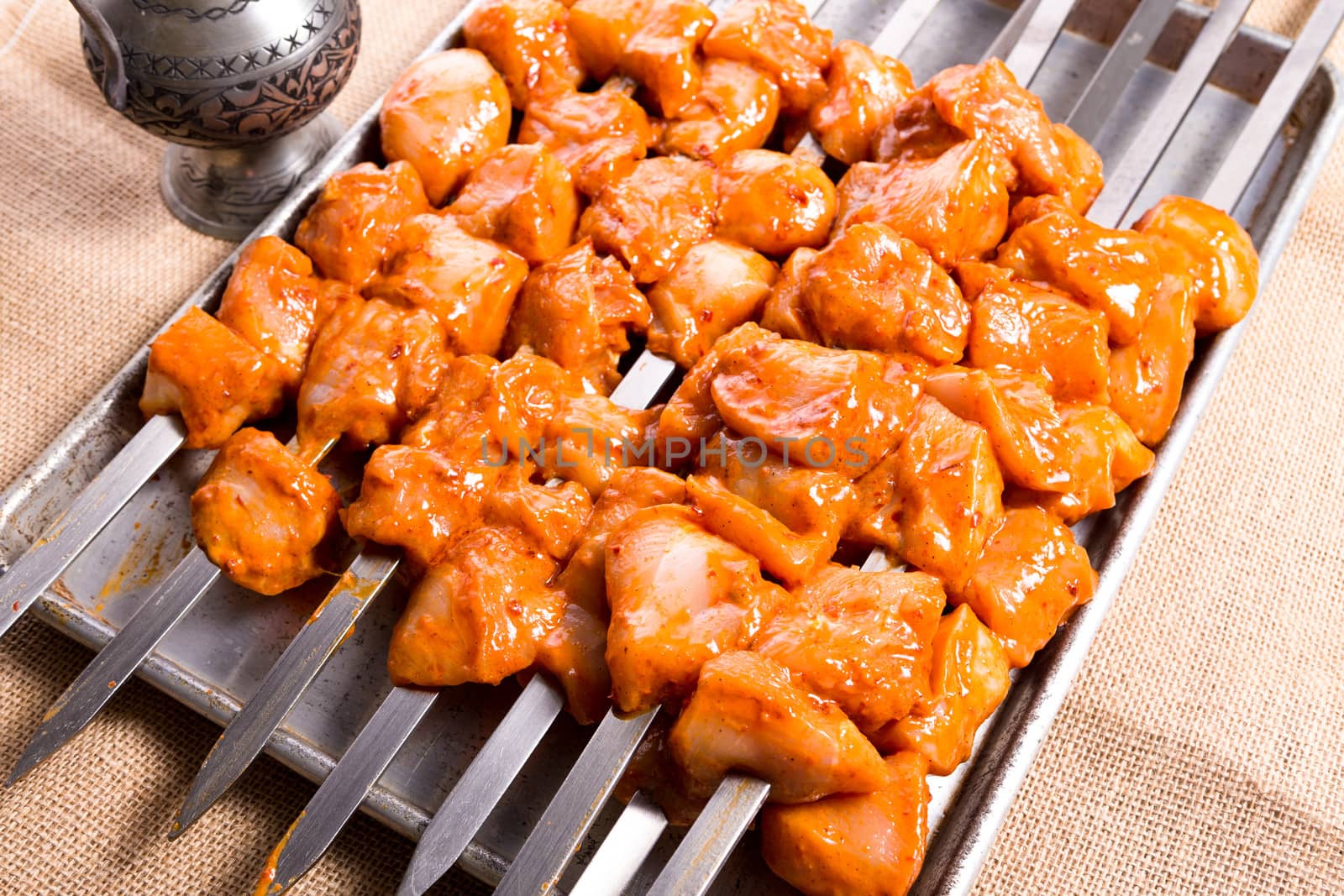 Well seasoned chicken skewers are waiting on aluminum tray, ready to go on to the grill and cook