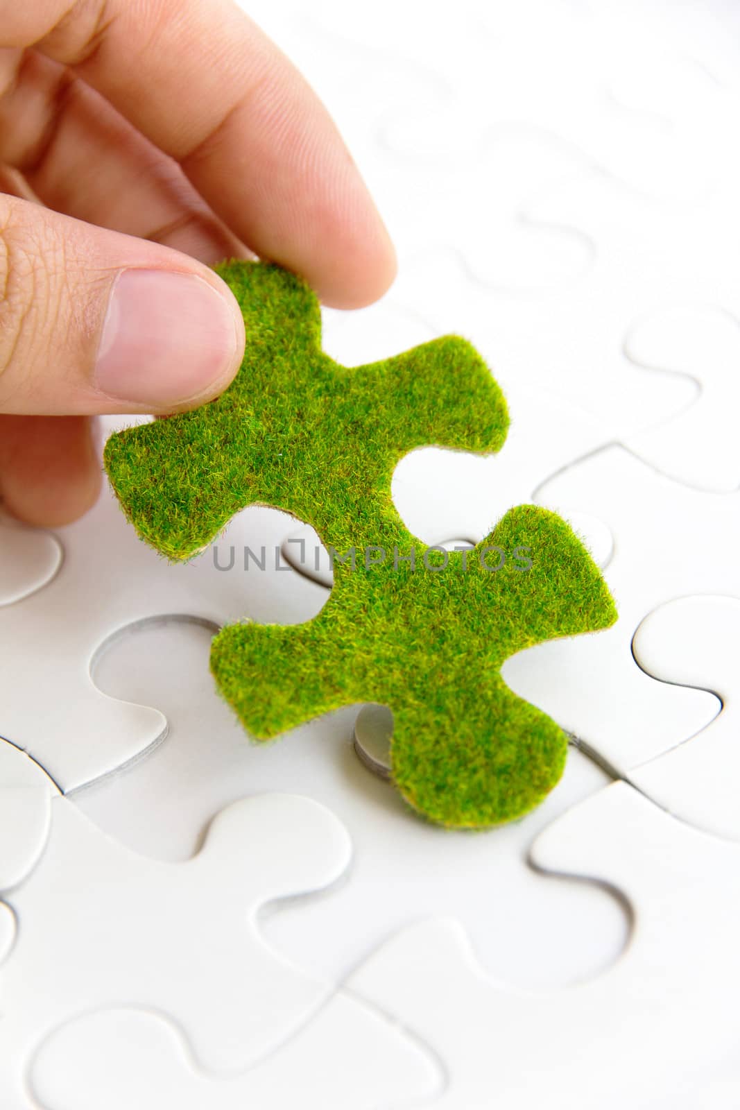 hand holding a green puzzle piece by ponsulak