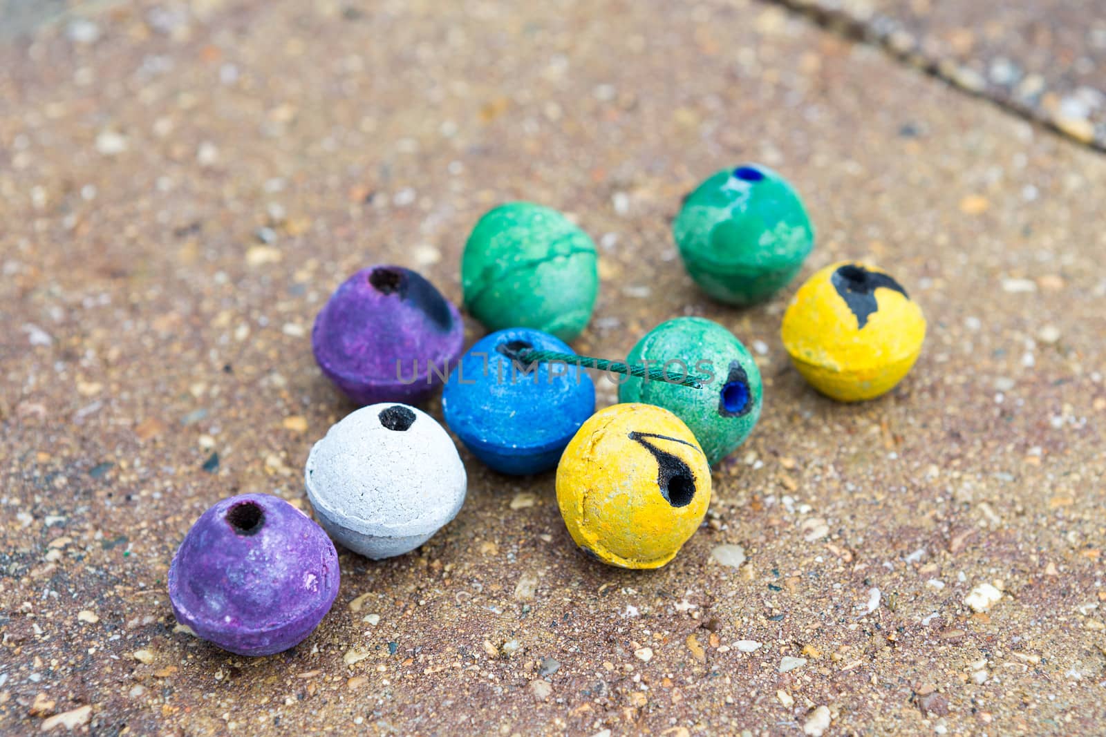 Colorful round smoke bombs naturally on the paver street some of them used some of them not. They have purple, green, yellow, white and blue colors, surely someone having fun