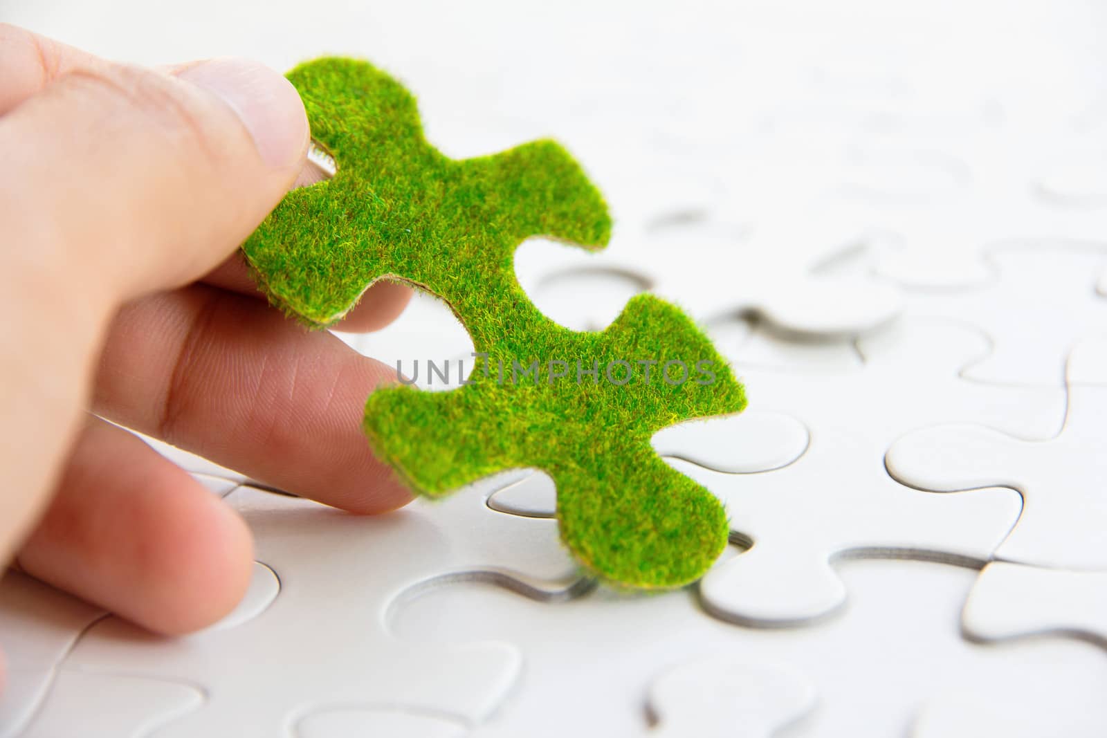 hand holding a green puzzle piece, green space concept
