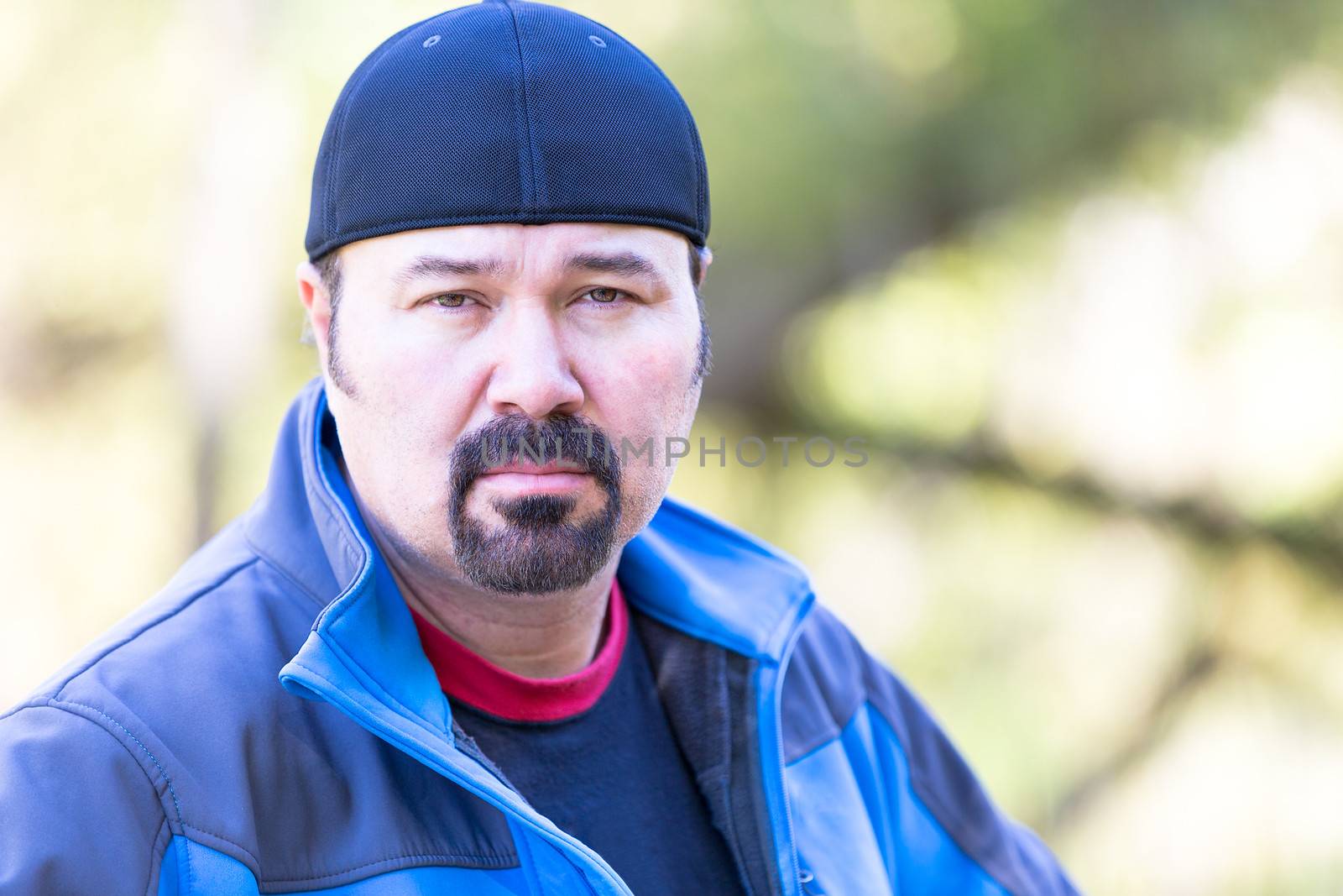 Man with a goatee looking determined attitude on a green sunny background