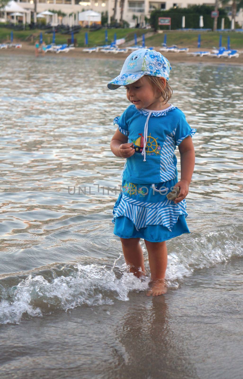 Two-year-old girl walking on sand seacoast                               