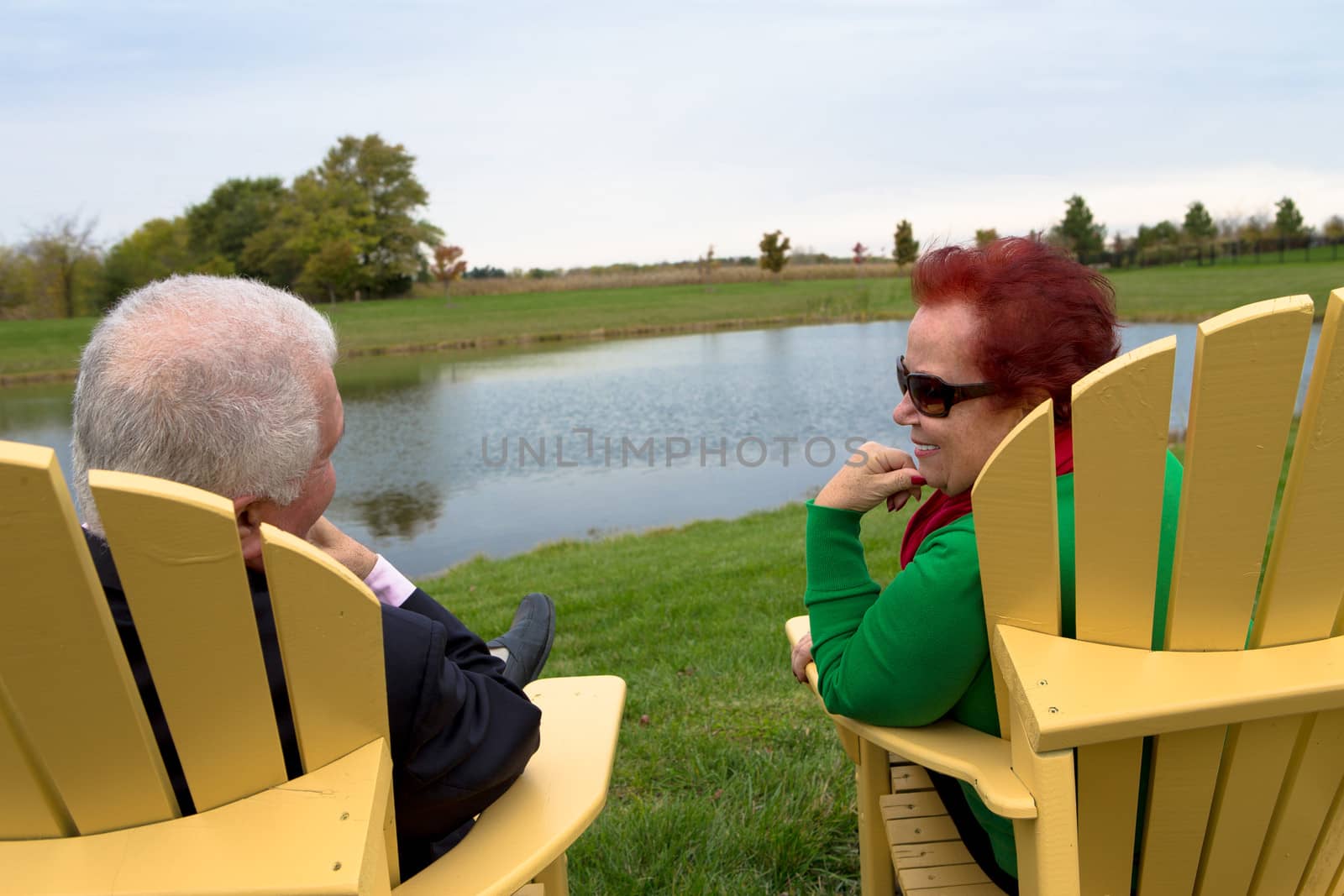Senior Couple enjoying their togetherness by the pond on the yellow beach chairs