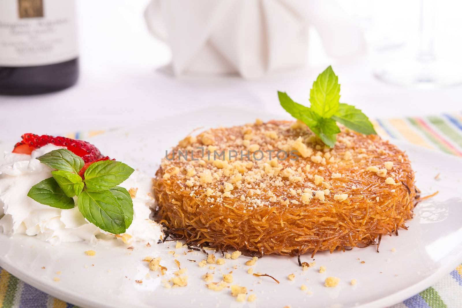 Turkish dessert kunefe with mint leaves, slices strawberry on a full fat cream and pinch of walnuts served after a nice meal