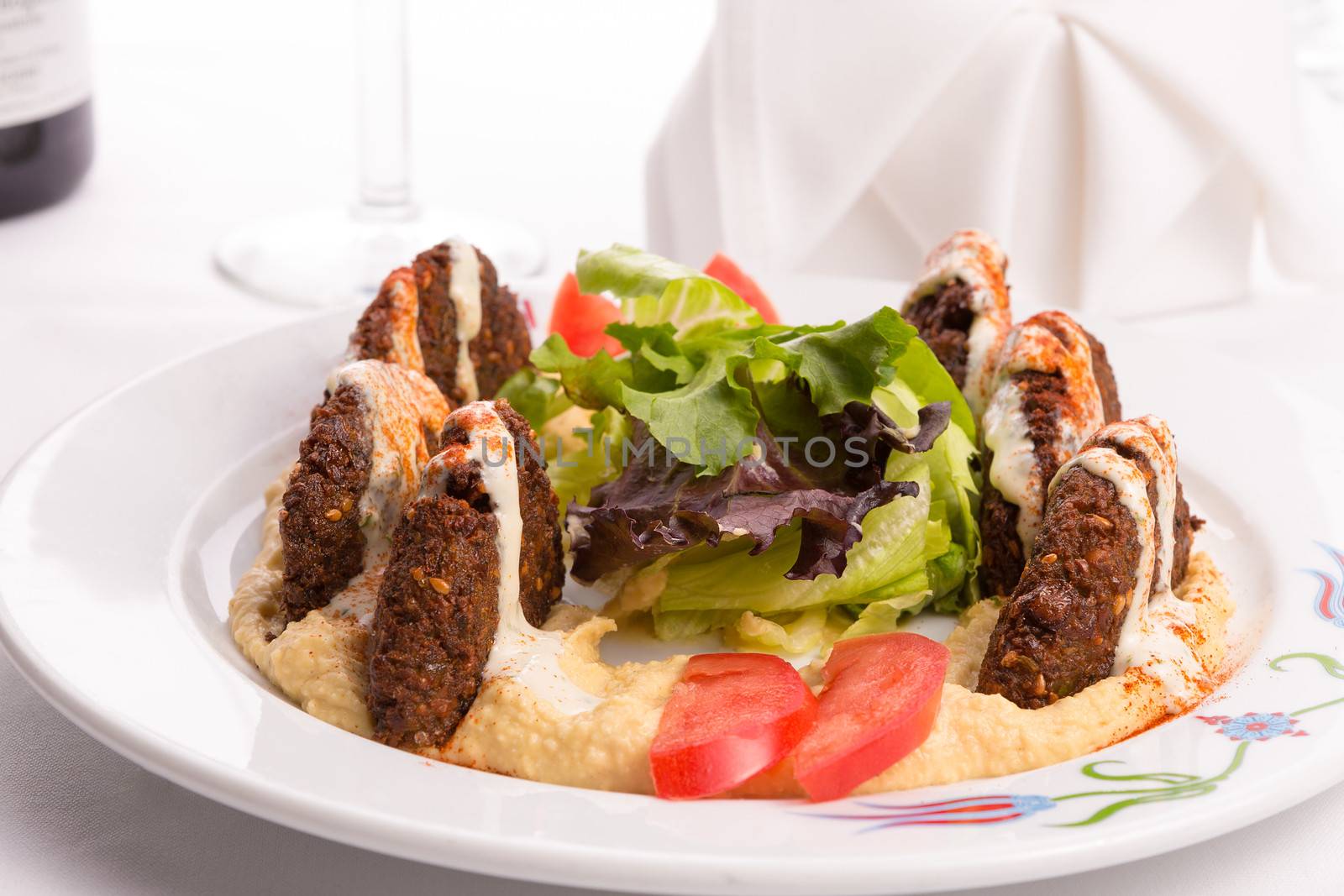 Fried half cut falafel patties of finely ground garbanzo beans spiced with parsley, cilantro and onion, laid on hummus and garnished with tomato slices and lettuce