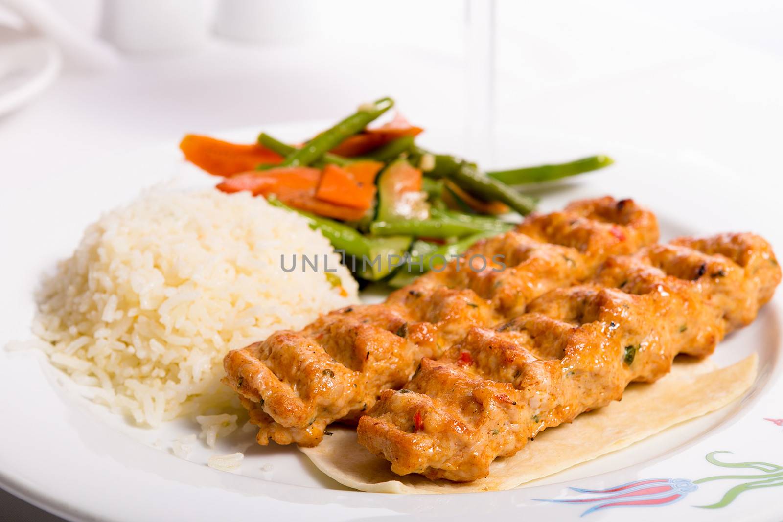 Chicken Adana kebap served with rice pilaf and green vegetables and some carrots