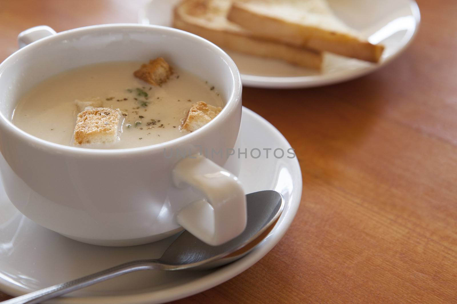 close up of mushroom soup in white ceramic cup on table top