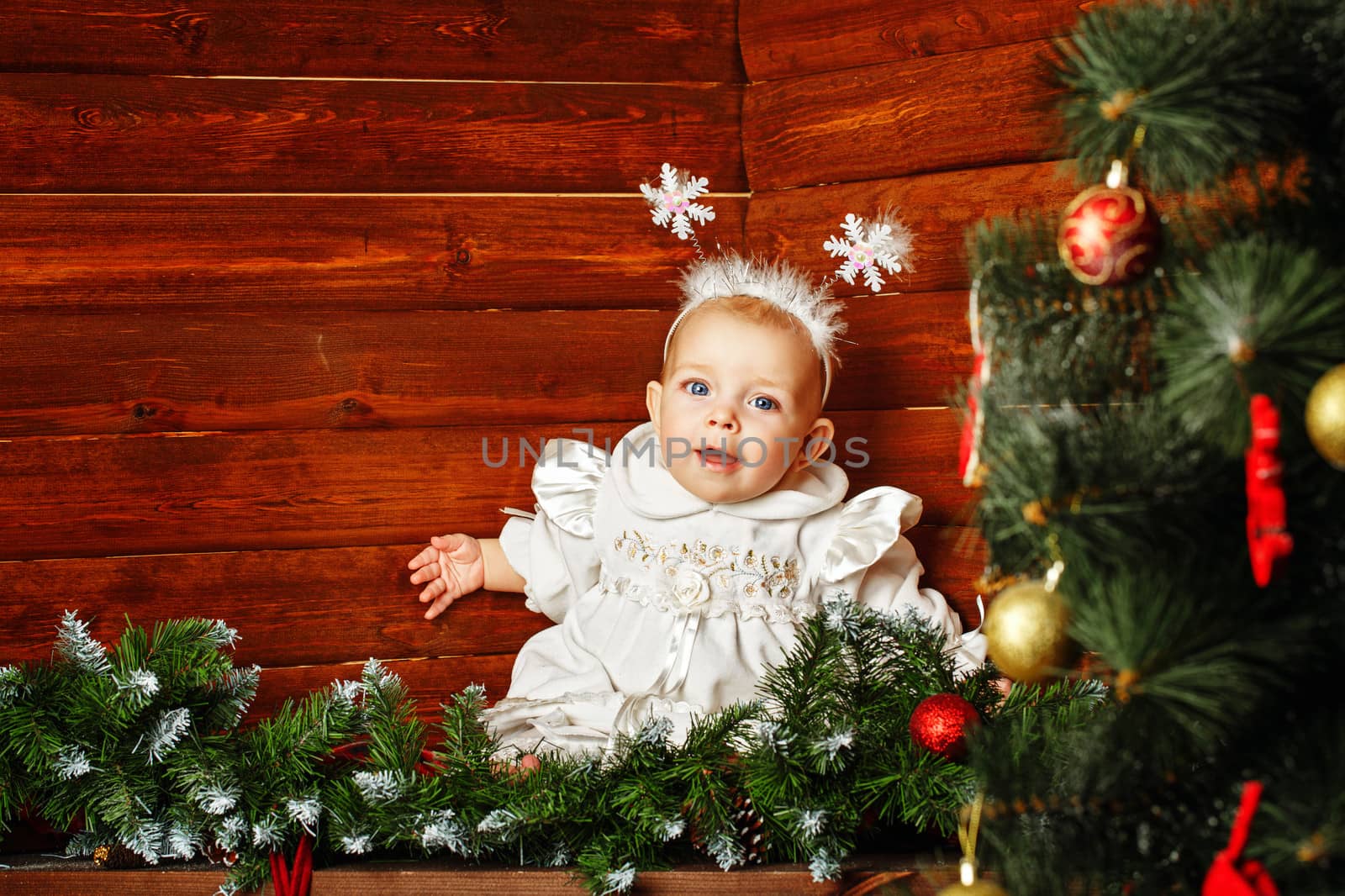 Cute little girl dressed as snowflakes near the Christmas tree and decorations