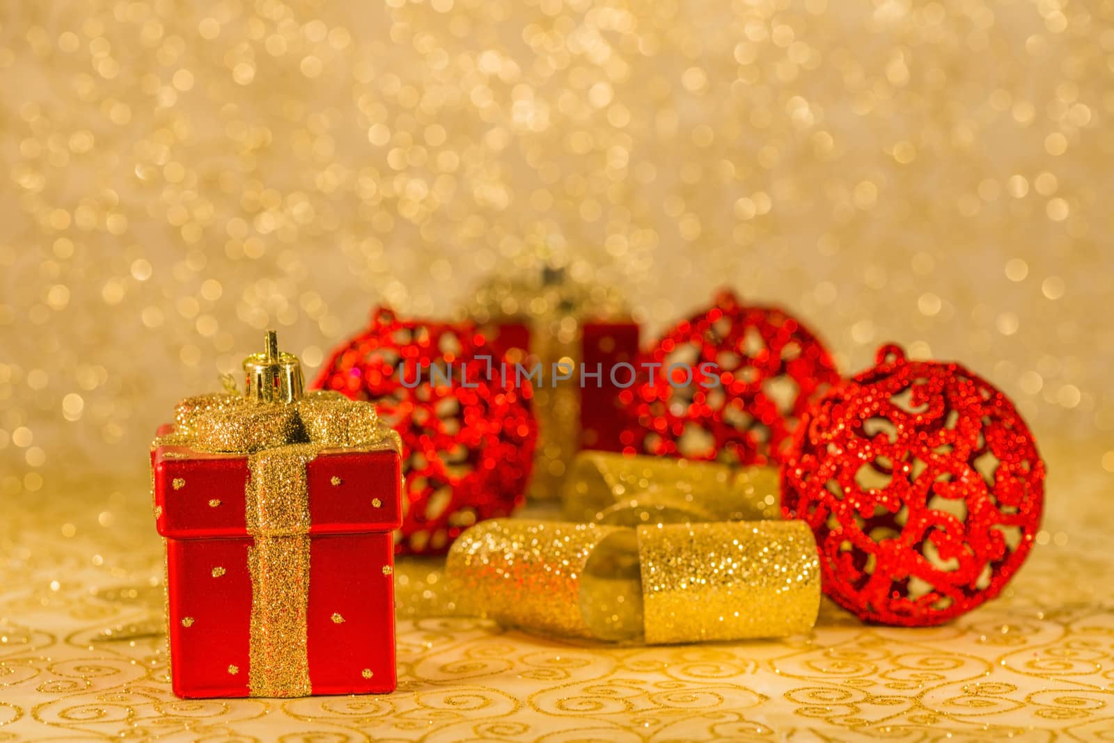 Red Christmas ornaments, golden ribbon and Christmas decoration on golden background