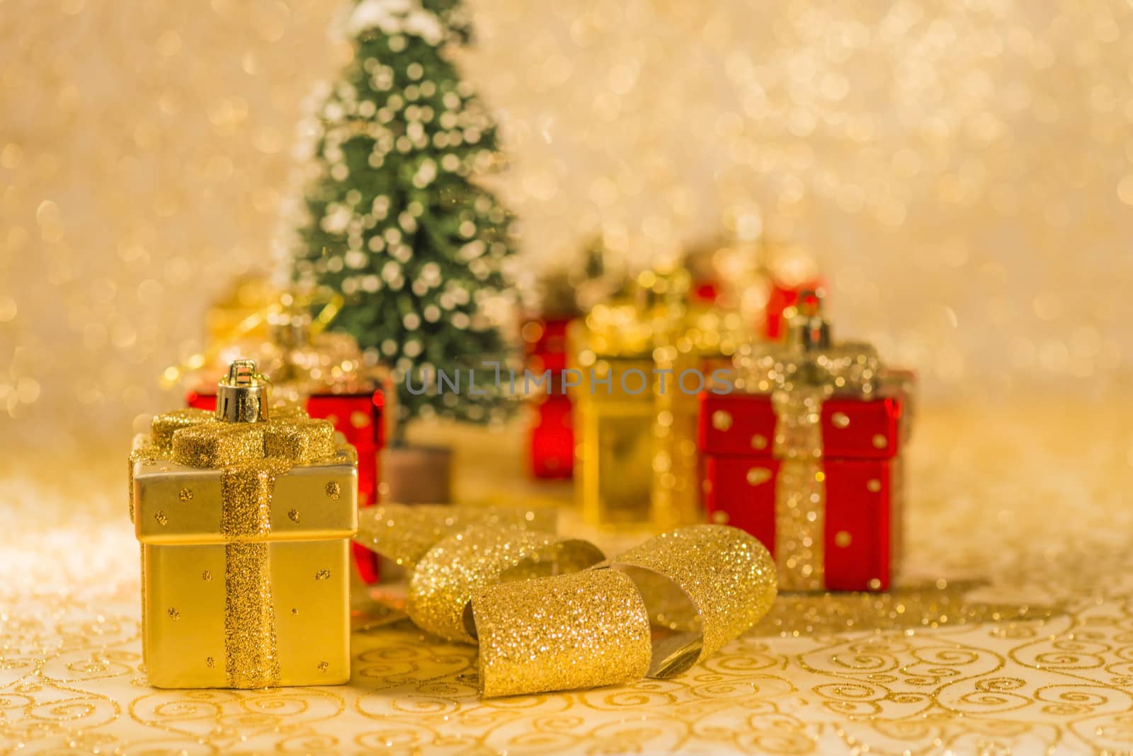 Red Christmas ornaments, golden ribbon and snowed Christmas tree on golden background