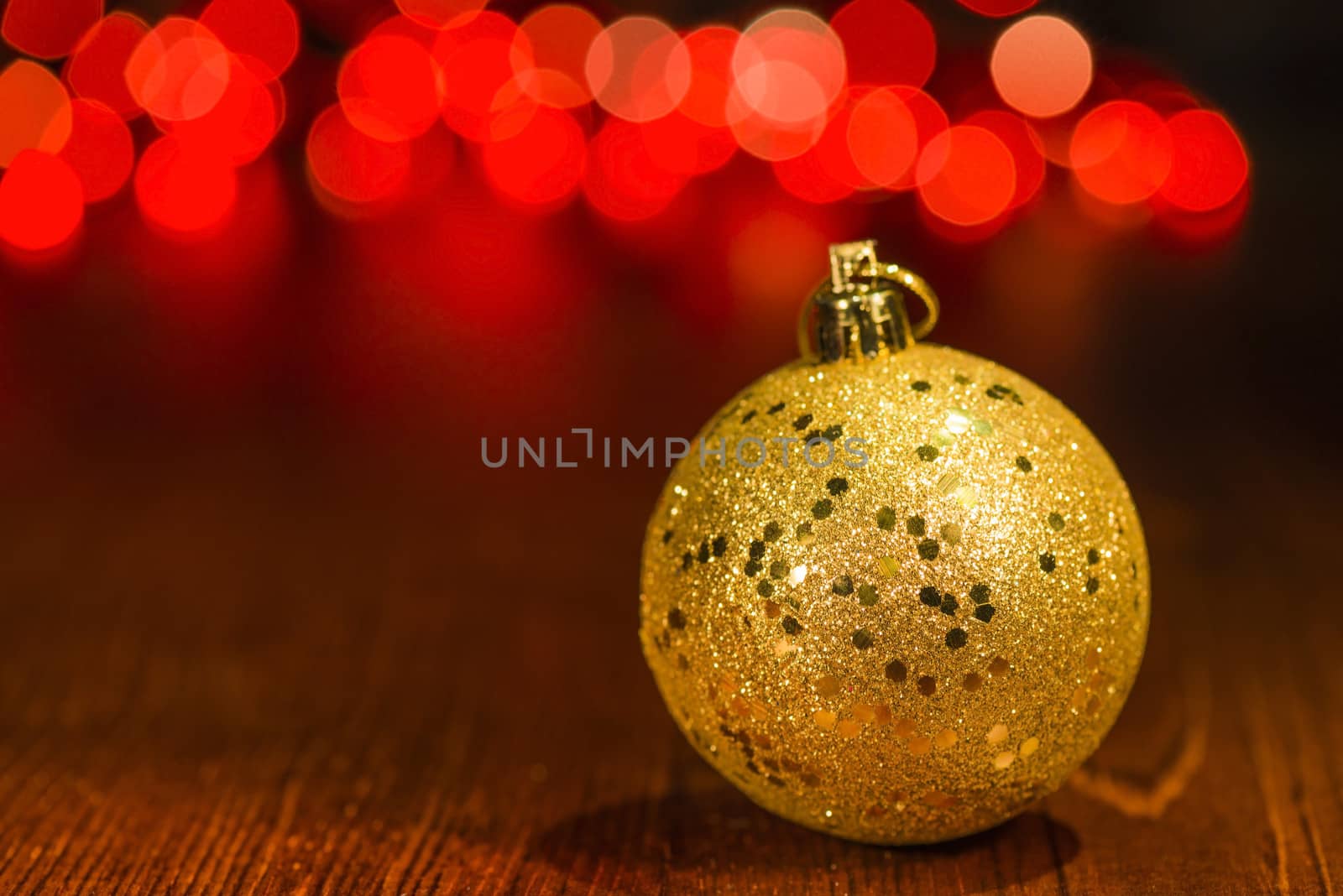 Golden Christmas ornament with red blur lights on wooden base