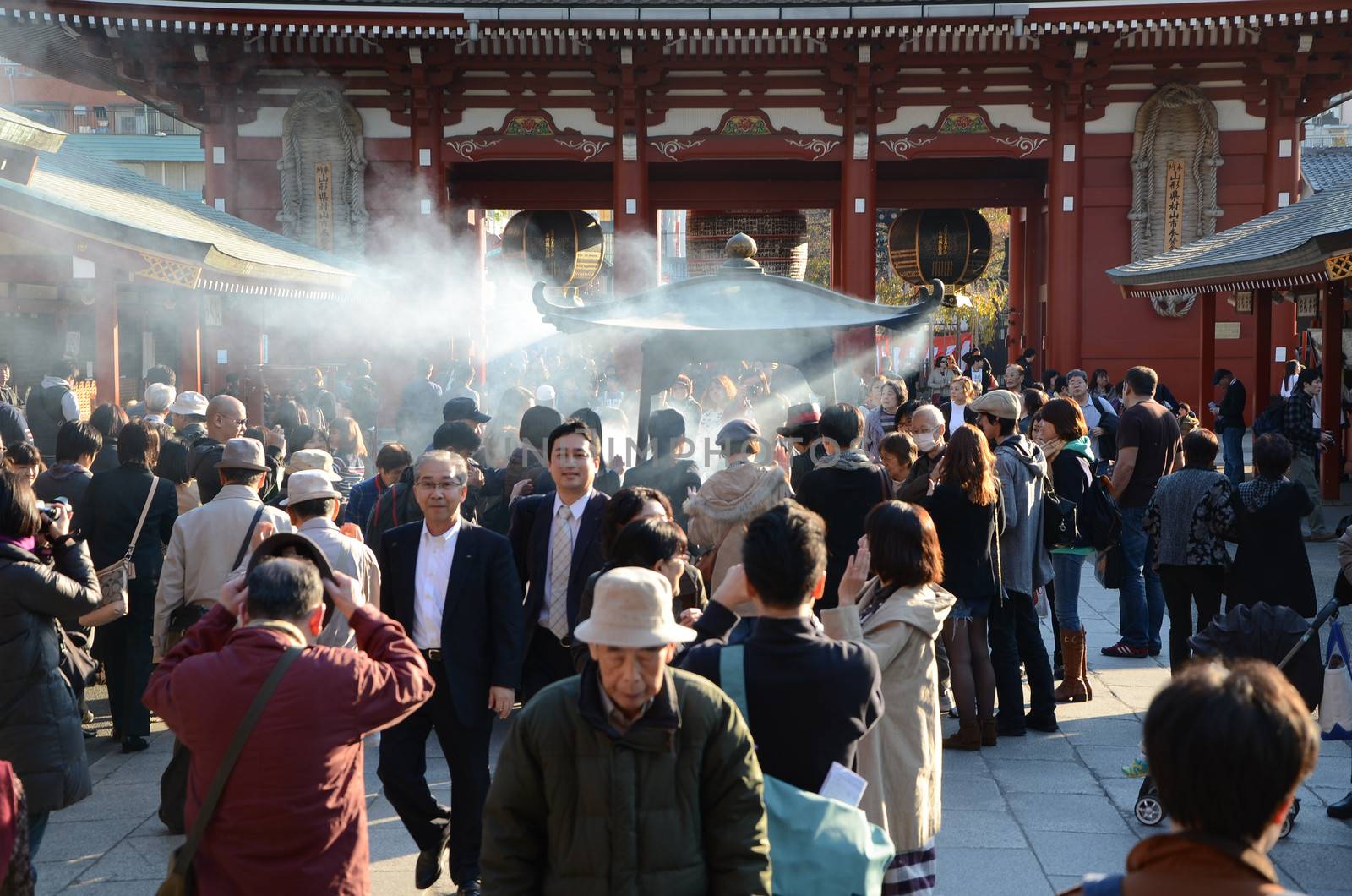 TOKYO, JAPAN - NOV 21: Buddhists gather around a fire to light incense and pray at Sensoji Temple on November 21, 2013 in Tokyo, Japan.