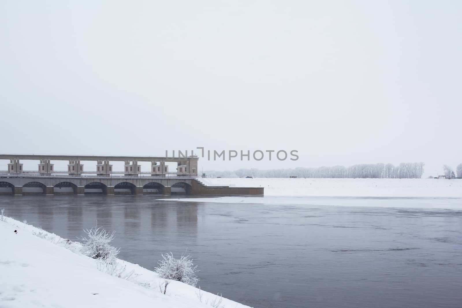 White tree, snow, river and dam in winter
