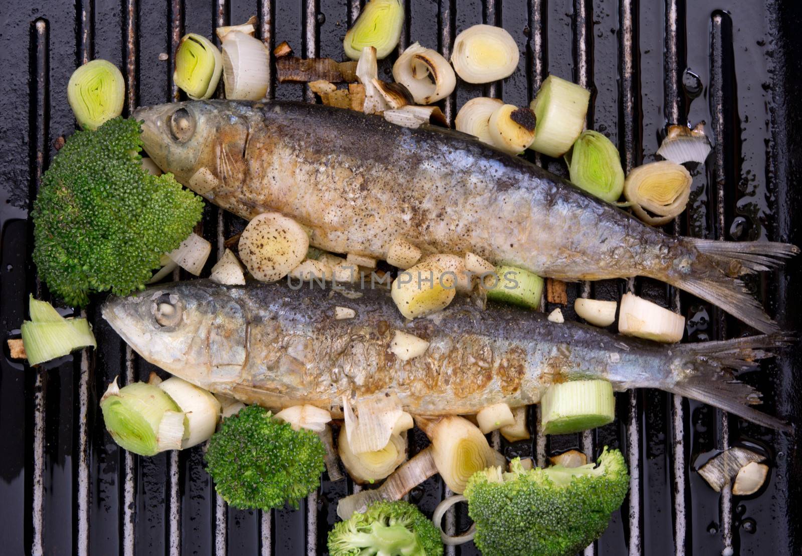Fresh sardines cooked on a griddle with leek and broccoli.