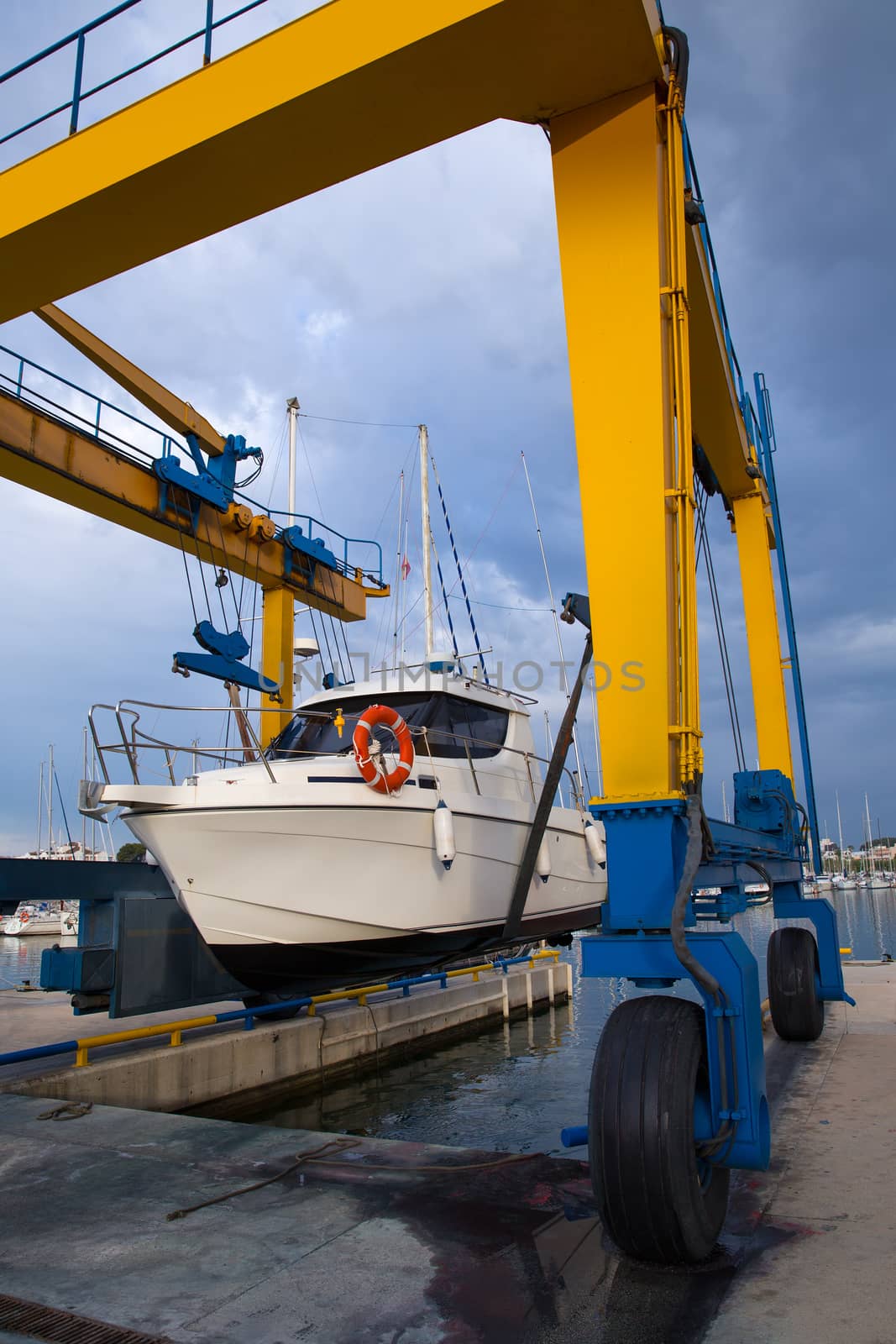 Boat wheel crane elevating motorboat to yearly paint by lunamarina