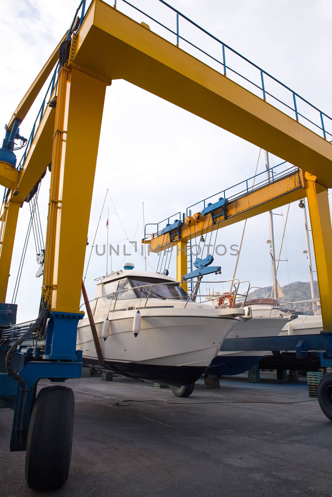 Boat wheel crane elevating motorboat to yearly paint by lunamarina
