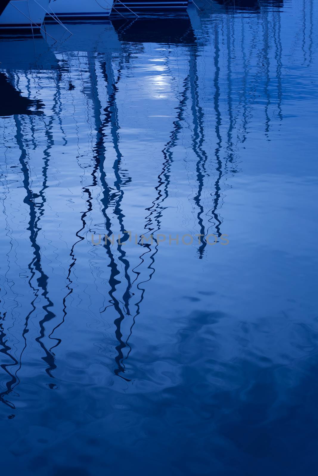 Blue water reflection of sailboats boats poles in waves by lunamarina