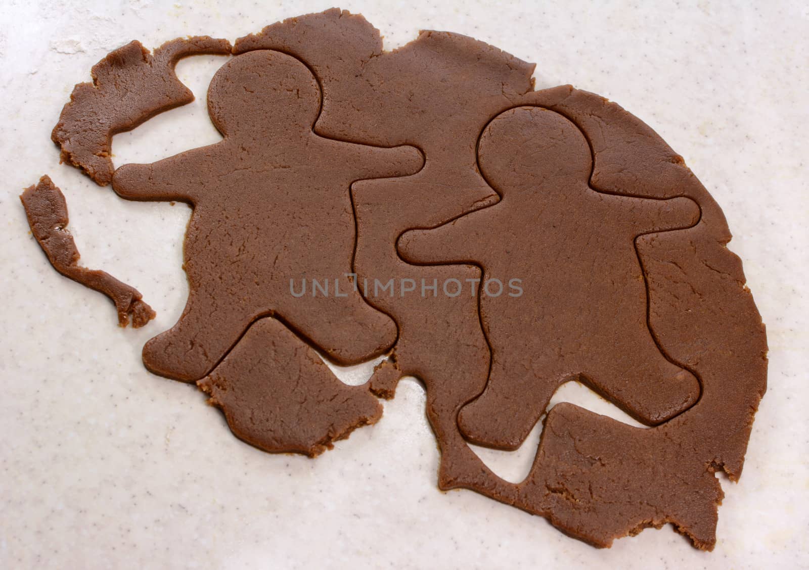 Two gingerbread men shapes cut into cookie dough