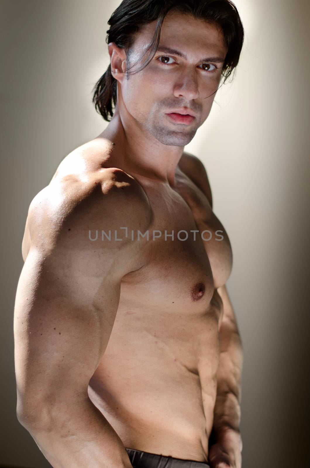 Shirtless muscular man on neutral background looking at camera