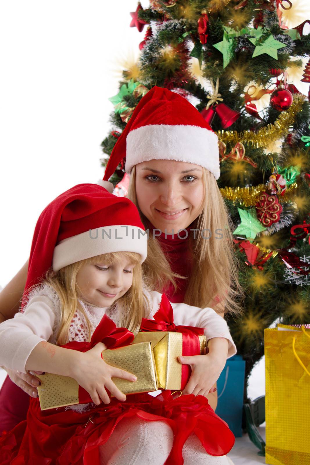 Smiling mother and little daughter with presents under Christmas tree