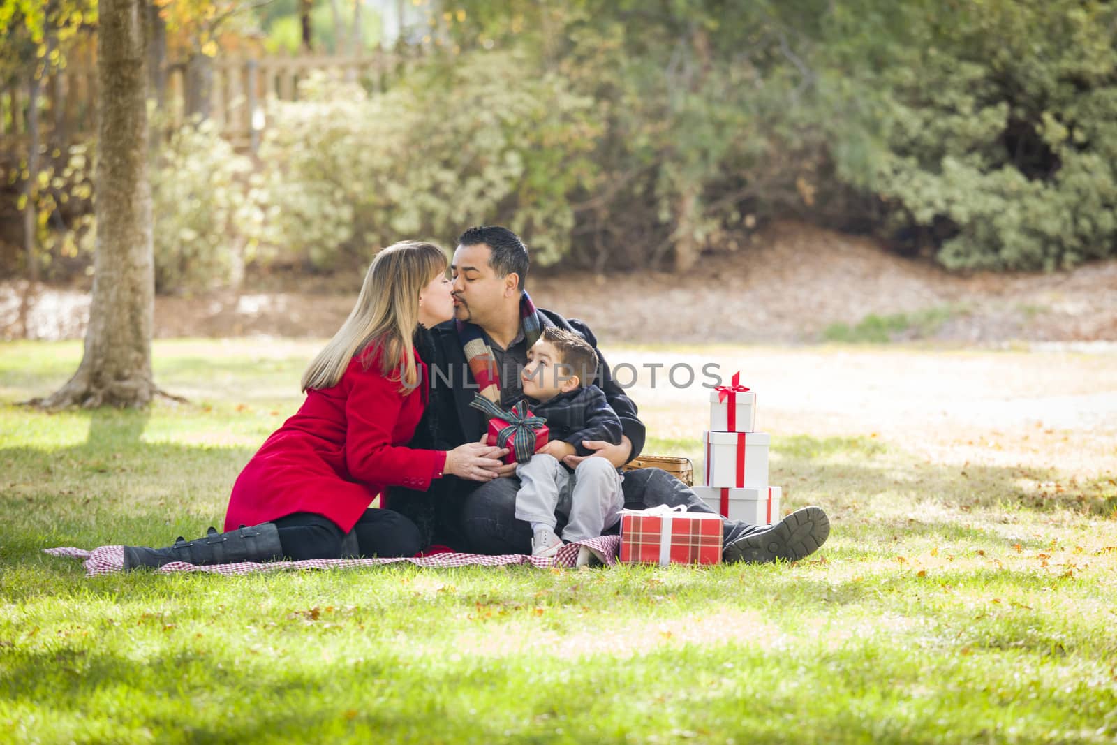 Young Mixed Race Family Enjoying Christmas Gifts in the Park Together.