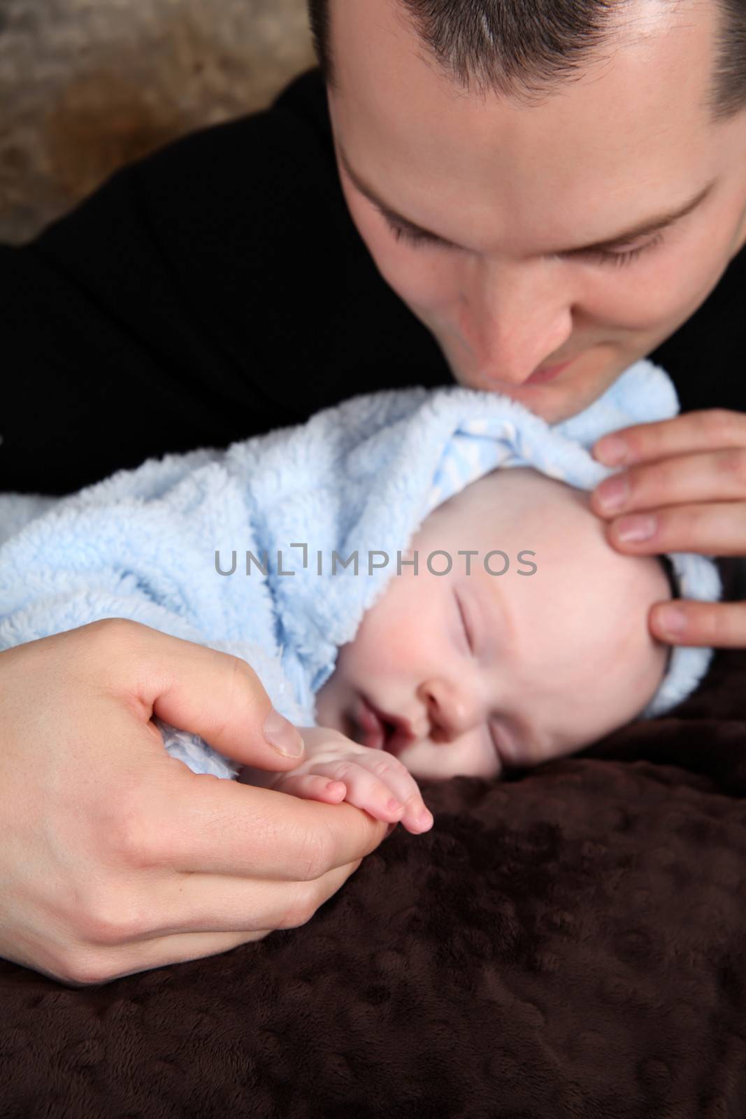 Baby boy sleeping while his father holds his hand