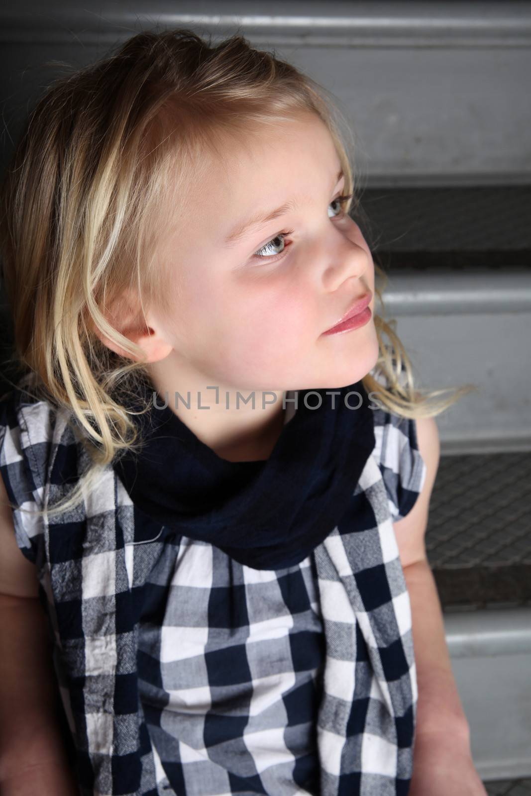 Blond girl sitting on staircase with serious expression