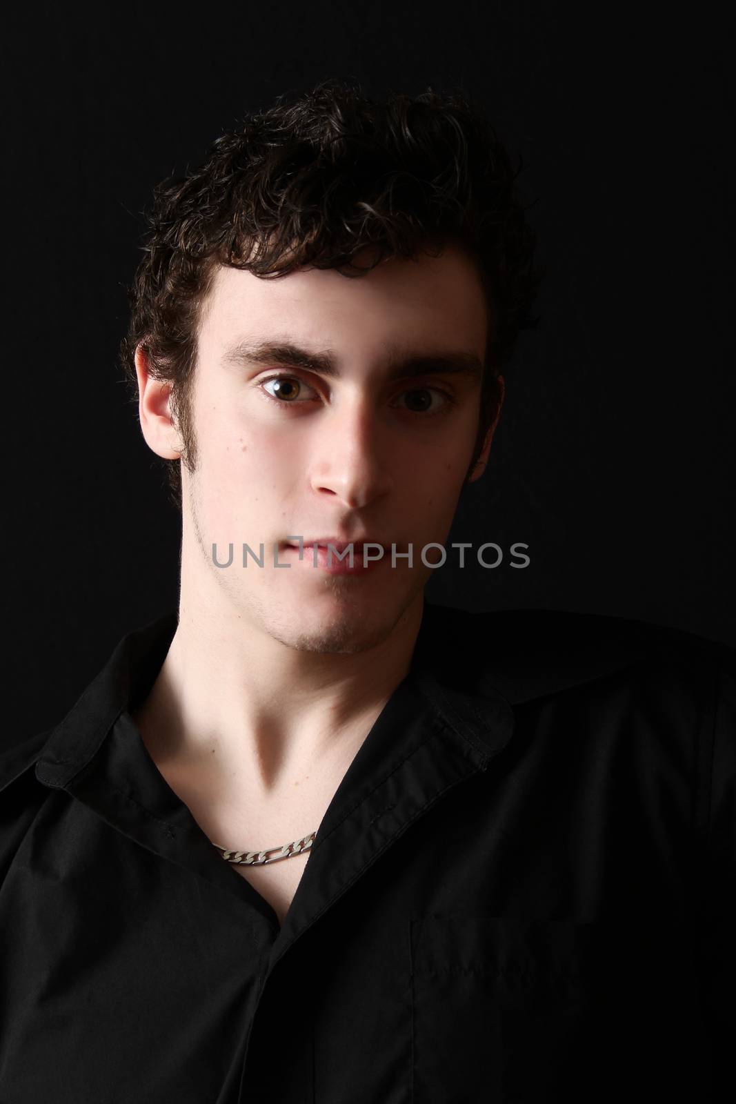 Attractive male model against black background with uneven lighting