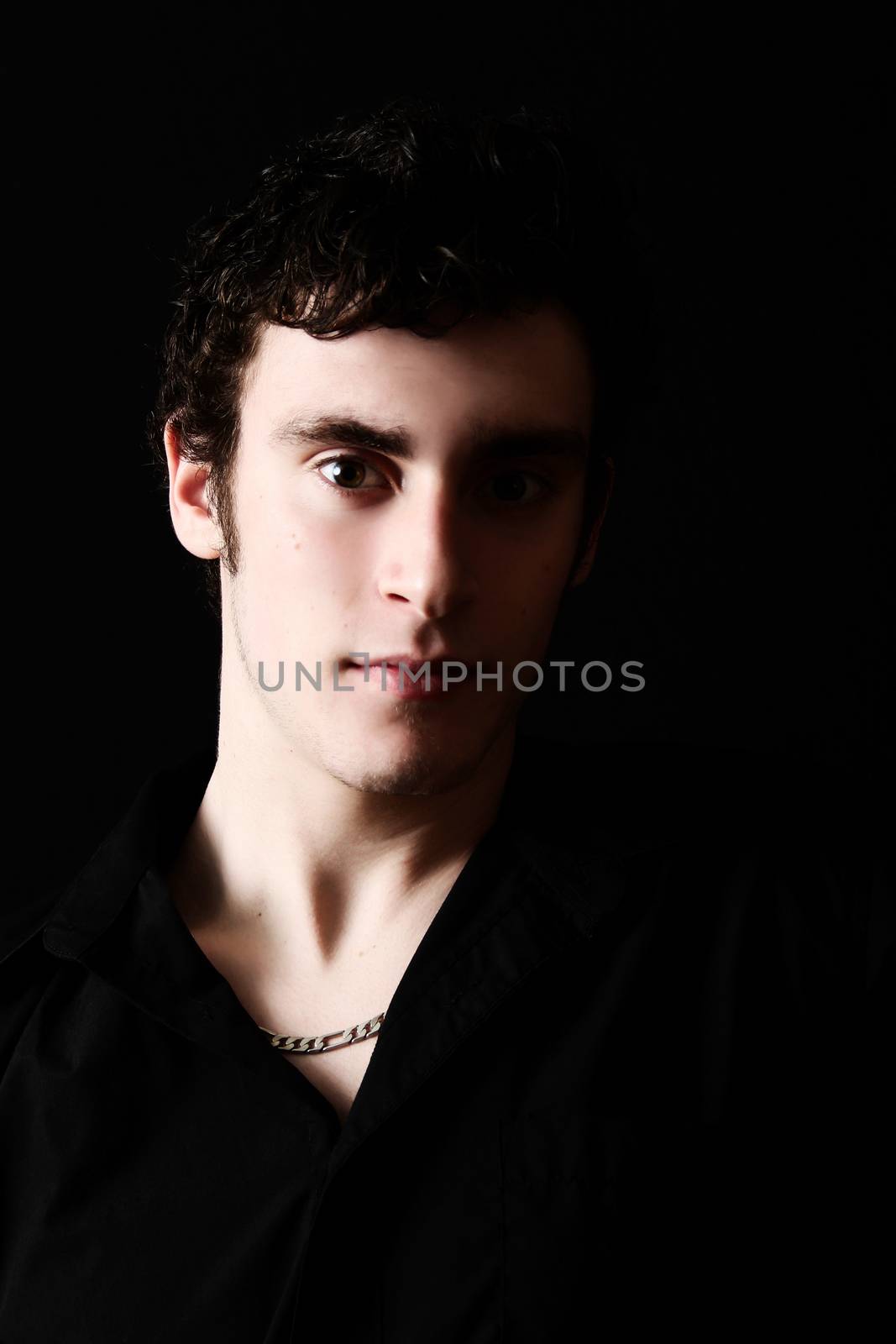 Attractive male model against black background with uneven lighting