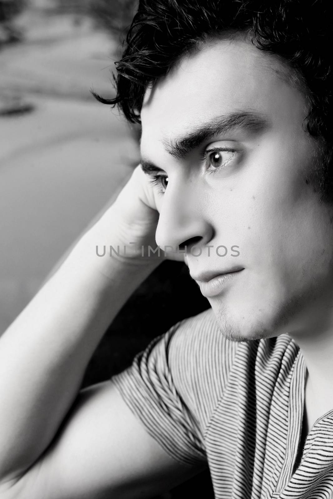 Attractive brunette male sitting by window in thought