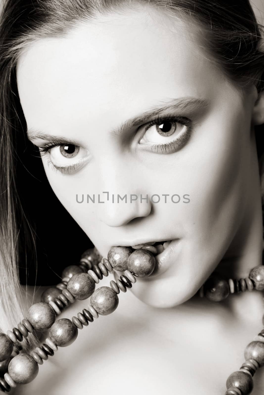 Beautiful blond female biting down on beads