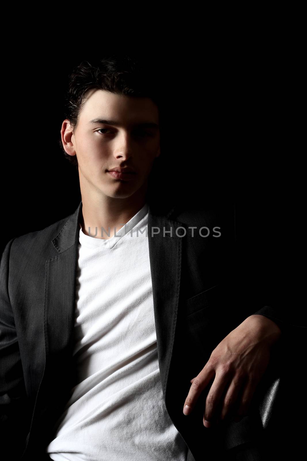 Attractive brunette male model on black background wearing white v-neck with jacket