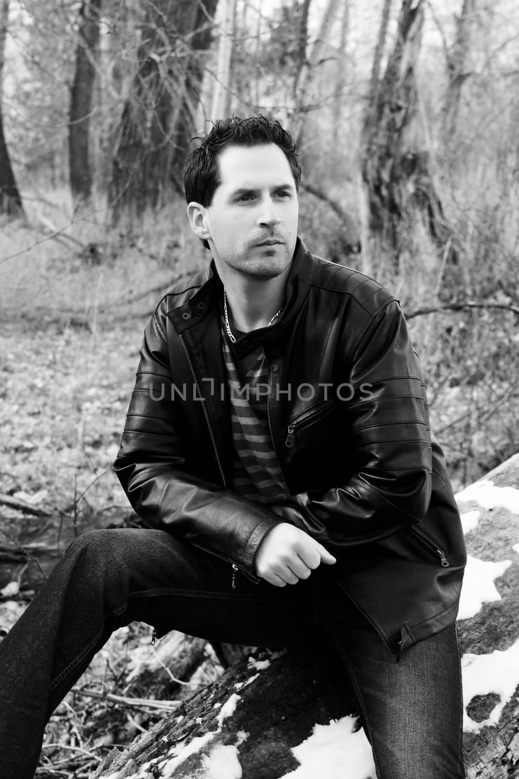 Brunette male model outdoors wearing leather jacket and jeans