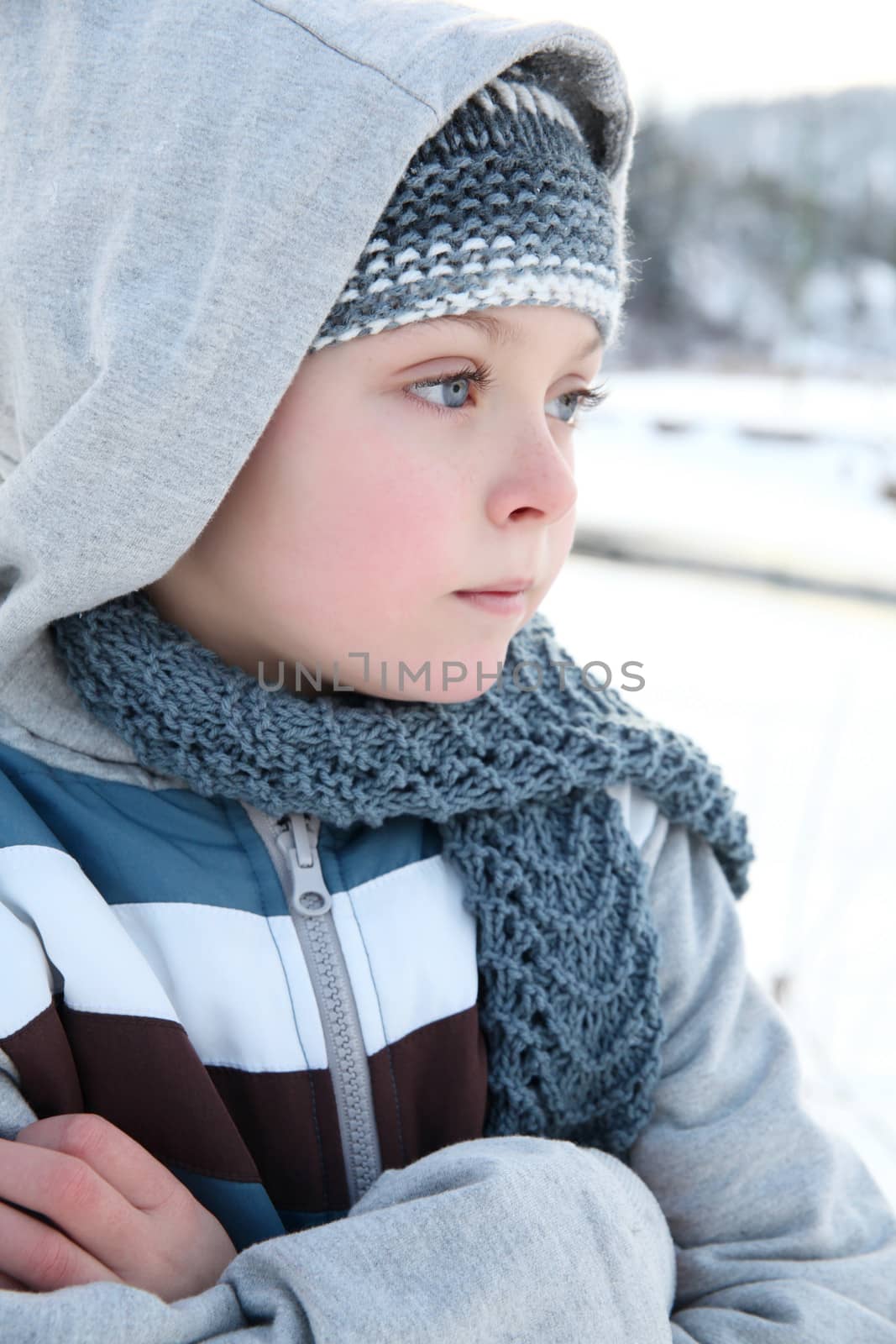 Young boy playing outside in the snow on a cold day