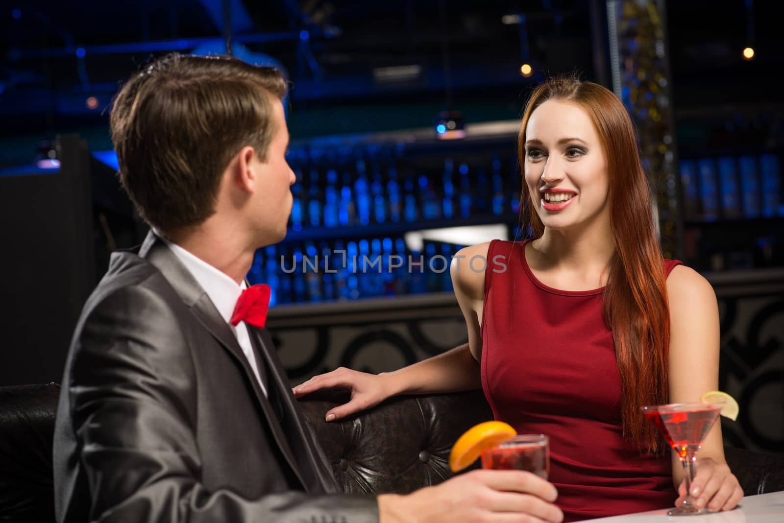 portrait of a woman in a nightclub, sitting on the couch and talking with man