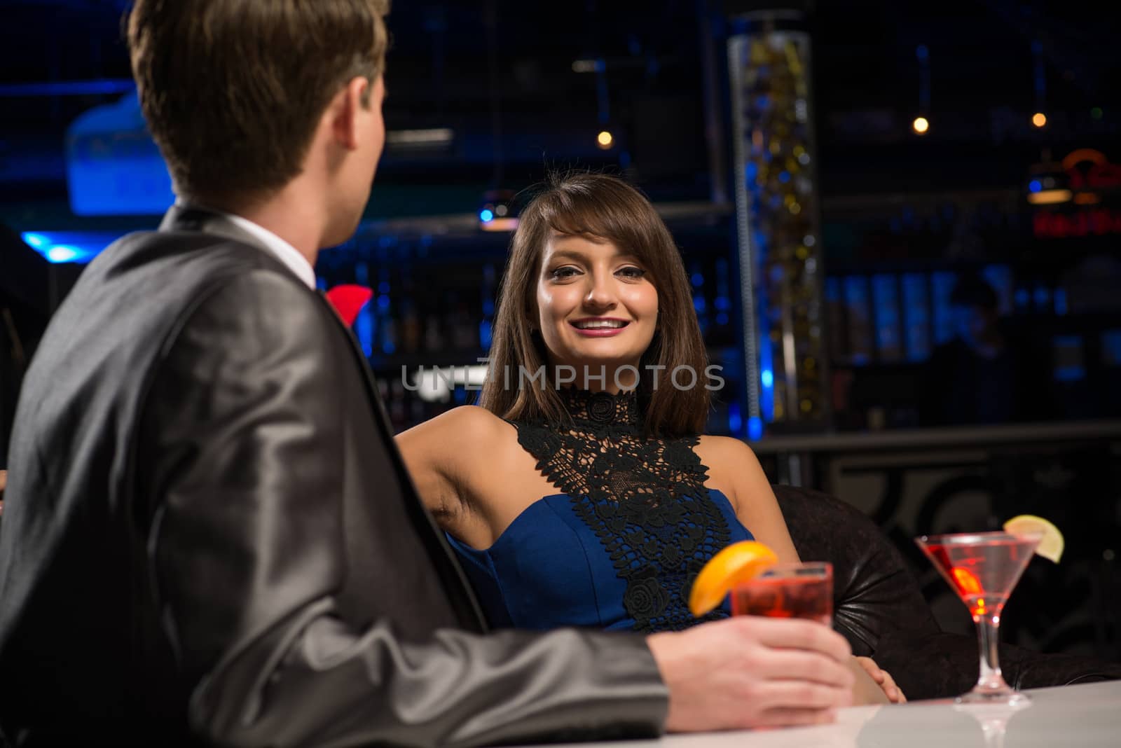 portrait of a woman in a nightclub, sitting on the couch and talking with man