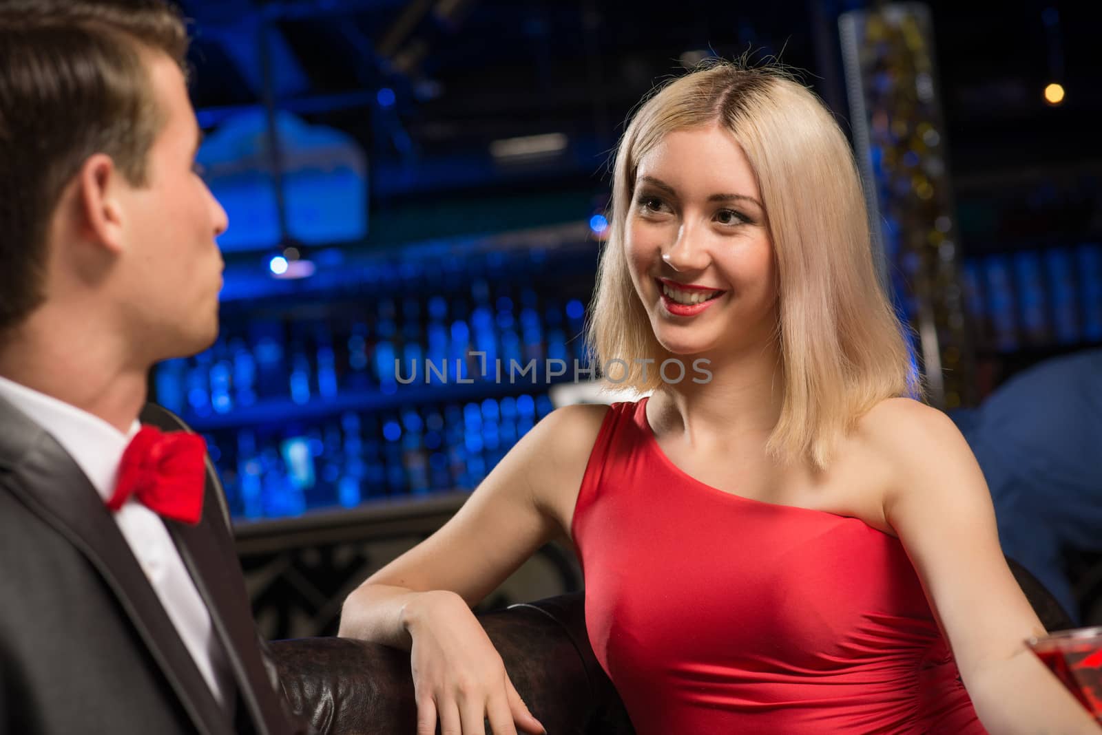 portrait of a woman in a nightclub, sitting on the couch and talking with man