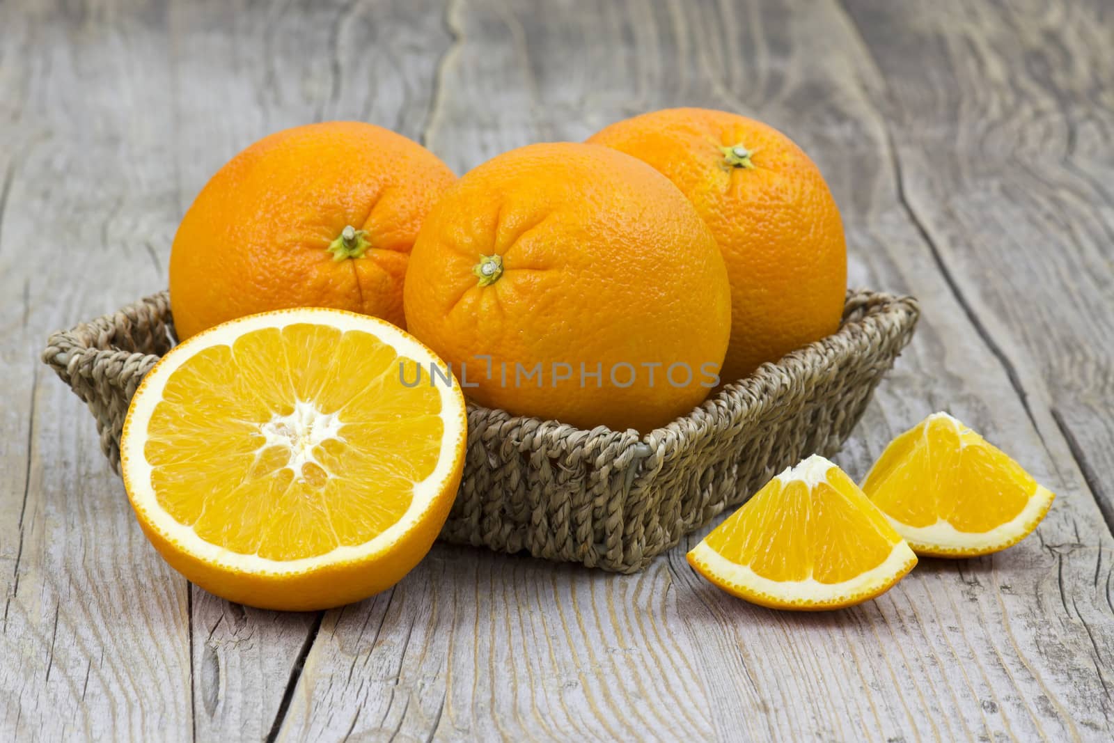 fresh oranges in a basket on old wooden background