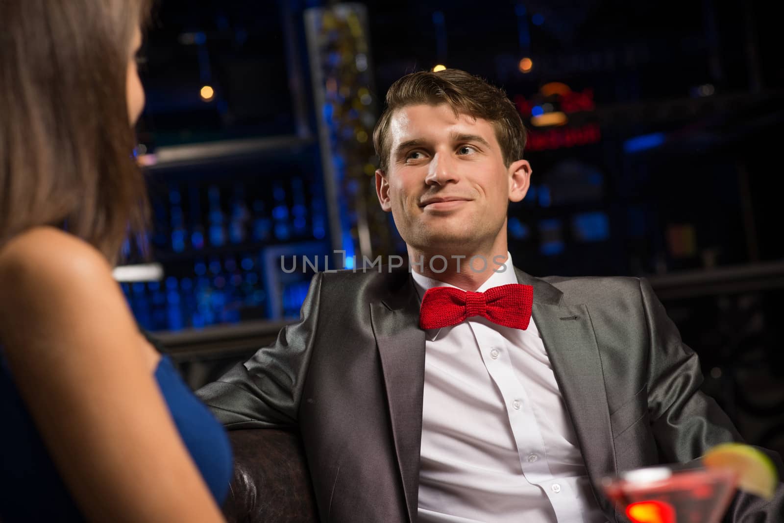 portrait of a man in a nightclub, sitting on the couch and talking with the woman, a date at a nightclub.