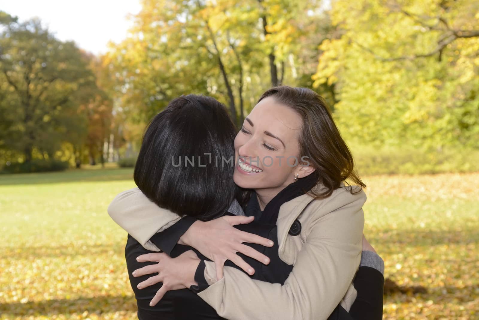  happy girlfriends hugging in autumn park