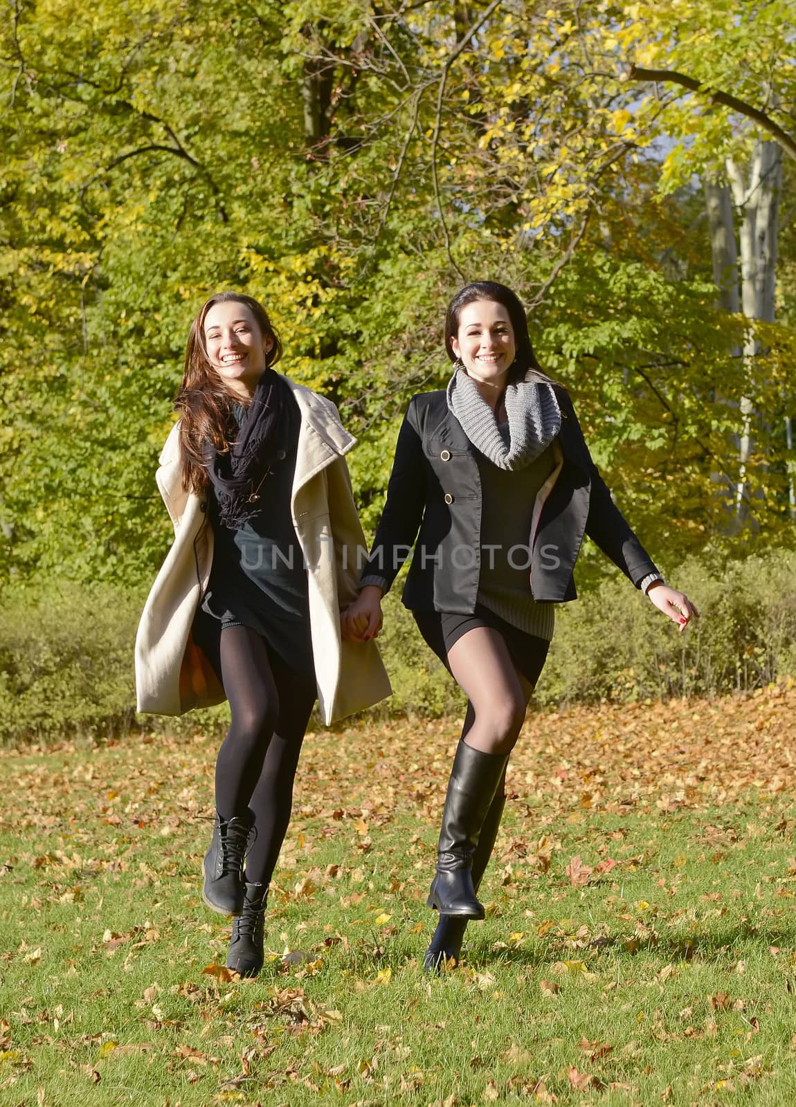 happy sisters running in autumn park