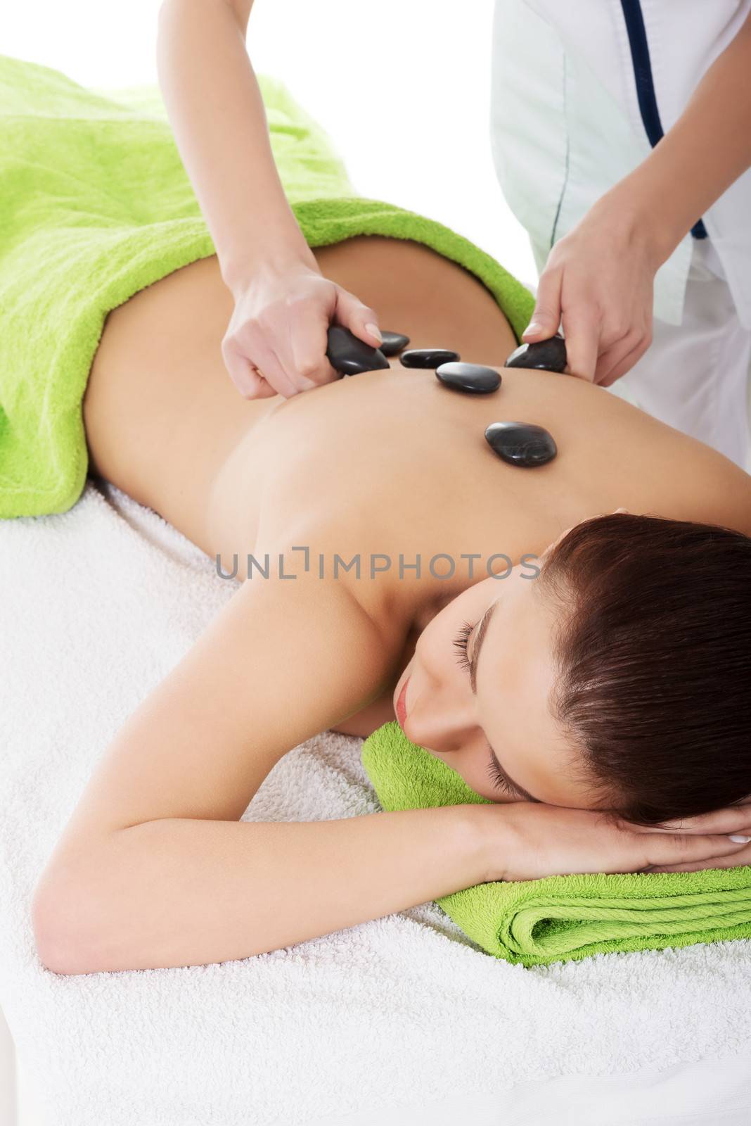 Beautiful woman lying on spa salon having stone massage. Spa concept.