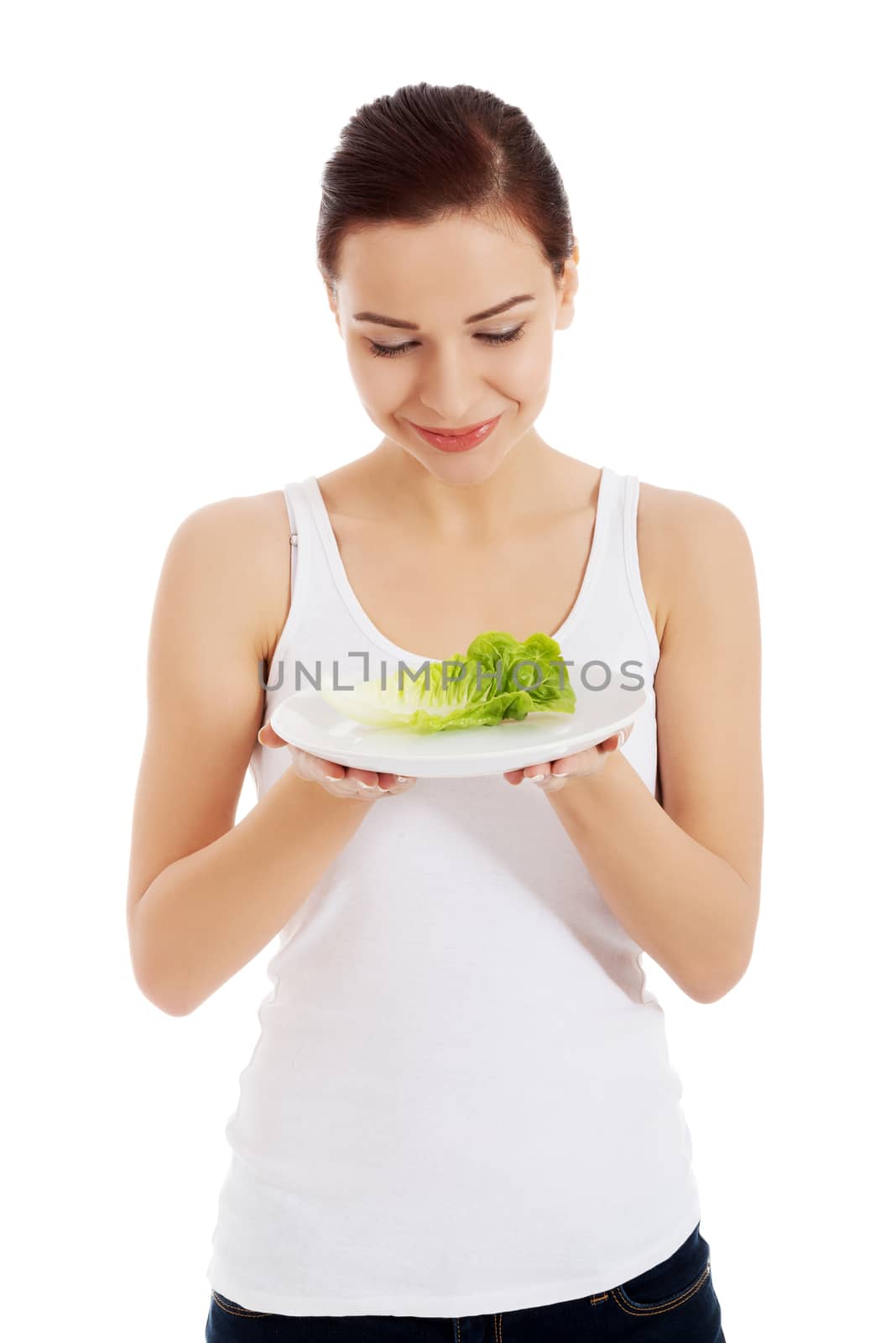 Young beautiful woman holding leaf of lettuce on table. Isolated on white.