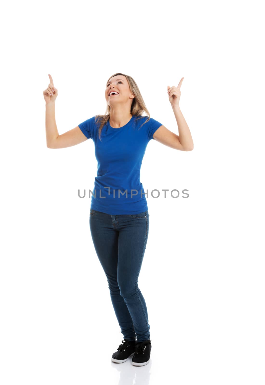 Young casual woman pointing up. Isolated on white.