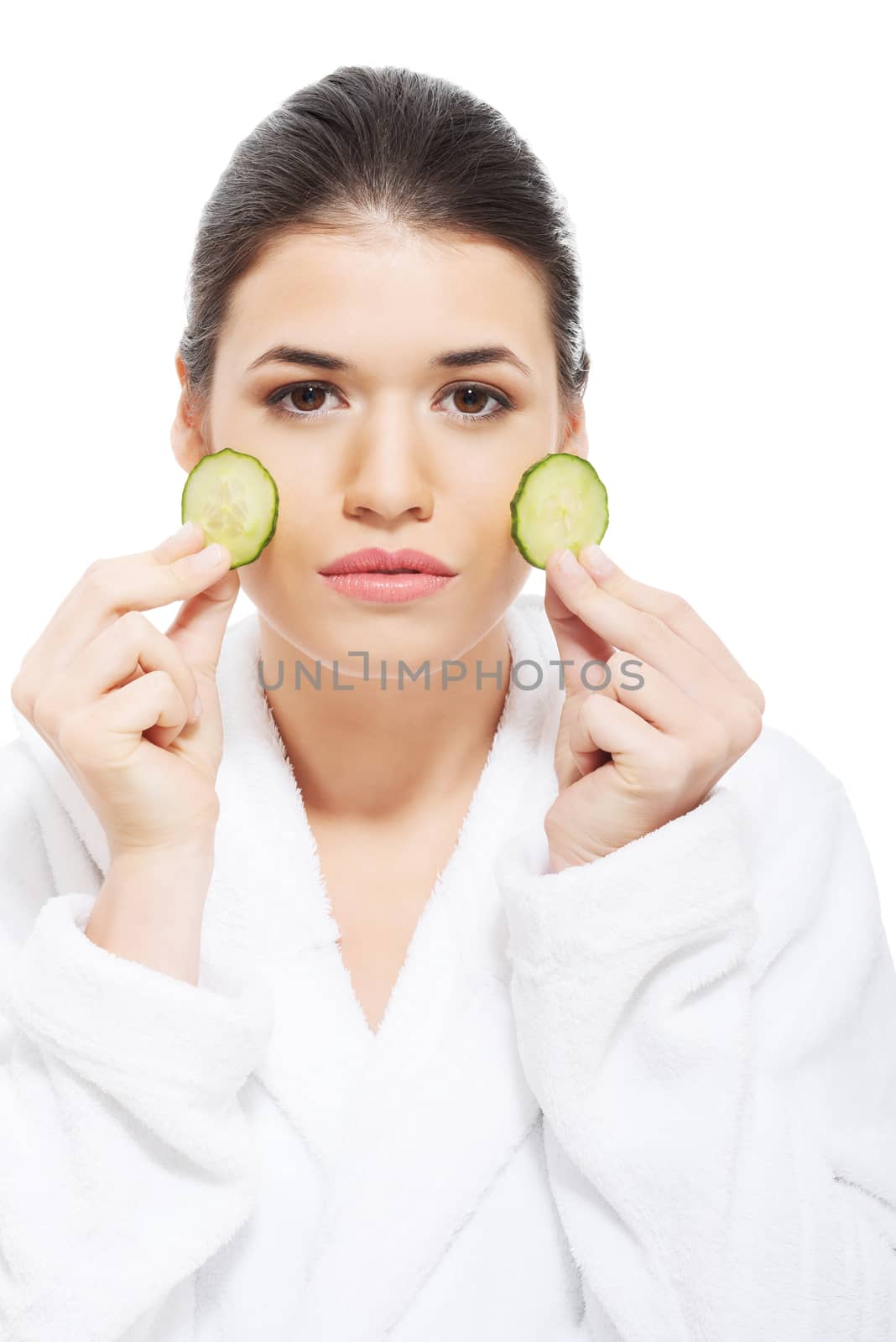 Beautiful woman in bathrobe holding slices of cucumber on her face. Isolated on white.